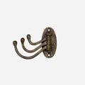 CC Interiors iron three swing hook in antique brass finish with oval wall backplate