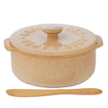 Beige ceramic baking dish with wooden knife on a white background
