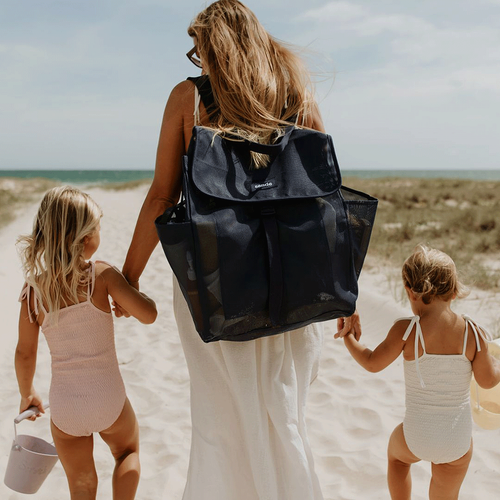 sande navy mesh beach backpack with flap top worn by woman walking on beach